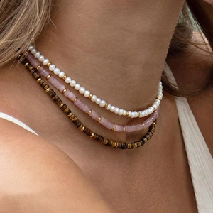 Detailed close-up of bohemian layered necklace with turquoise and amethyst beads on neck