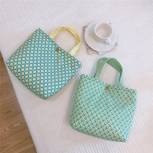 Close-up of floral canvas tote bags with snap buttons on a cozy white bed background