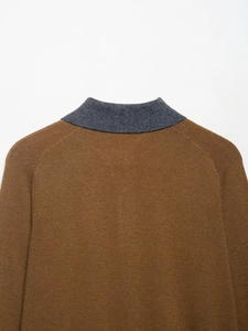 Detail of the high-quality knit texture and contrast charcoal collar on brown polo sweater