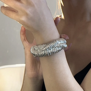 Close-up of a silver wide cuff bracelet with heavy texture worn on a woman wrist