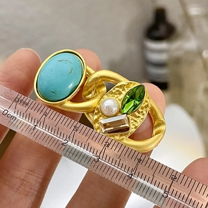 Close-up of vintage golden brooch with turquoise and pearl measuring 5 cm long