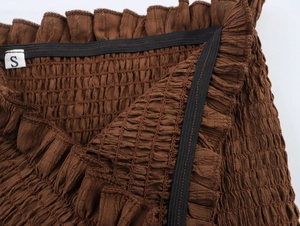 Detail of brown smocked fabric with elastic band and size S label on back