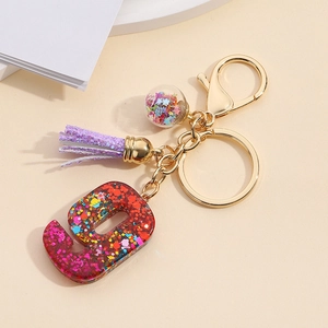 Detail of resin number 9 keychain with colorful sequins, purple tassel, and gold hardware