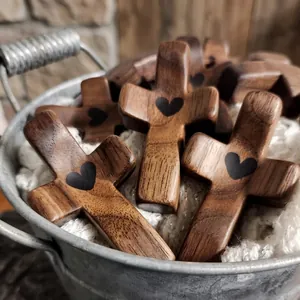Handheld walnut wood cross with black heart inlay shown in a rustic metal bucket