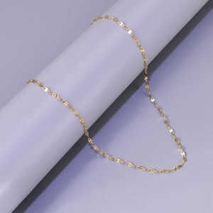 Nahaufnahme einer goldenen Edelstahl-Gliederkette auf einem grauen Sockel