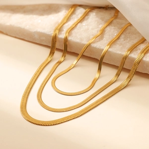 Three layered golden snake bone necklaces on silk background with professional soft lighting