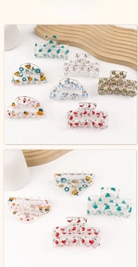 Detail of transparent acrylic Christmas hair claws with festive gingerbread and tree patterns