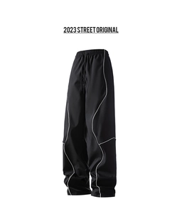 Close-up of black high-waisted wide-leg trousers with white curved piping details