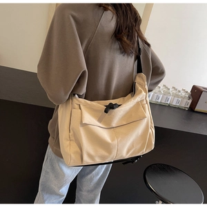 Detail of canvas tote bag showing contrast black rope zipper and functional front pocket