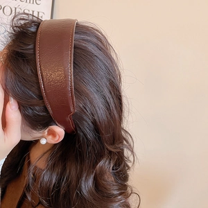 Detail view of brown lychee-textured leather headband on model with high crown design