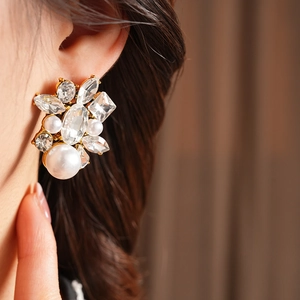 Close-up of vintage baroque gold earrings with teardrop pearls and crystals on a model