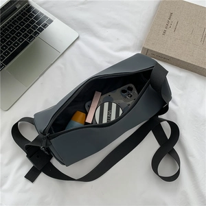 Sac cylindrique gris foncé avec bandoulière réglable présenté en vue à plat lifestyle