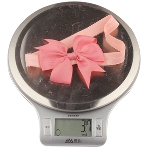 Close-up of lightweight pink ribbon bow headband weighing only 3.7g on digital scale