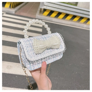 Detailed view of light blue tweed mini purse featuring pearl handle and bow accent