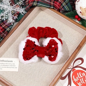 Macro view of Christmas red velvet bow scrunchie with sequins and white faux fur trim