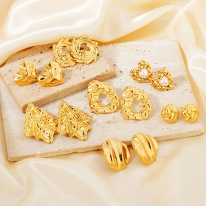 Set of gold geometric stainless steel earrings with pearls on champagne satin silk background