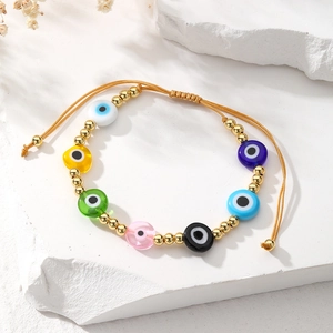 Detail of bohemian evil eye bracelet with colorful beads and adjustable gold cord