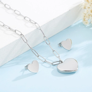 Vue détaillée de l'ensemble collier à pendentif cœur argenté et boucles d'oreilles clous