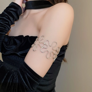 Close-up of polished silver hollow flower arm cuff worn on model's upper arm
