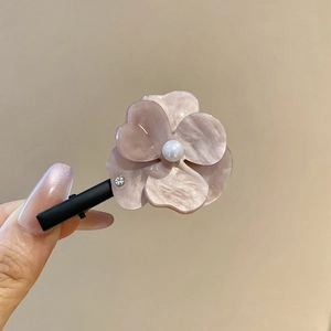 Détail macro d'une pince à cheveux fleur en résine avec perle et texture marbrée