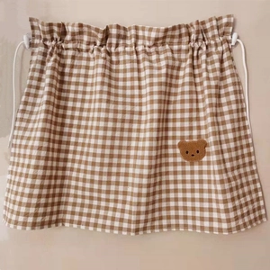 Detailed view of checkered fabric storage bag with drawstring and cute bear embroidery