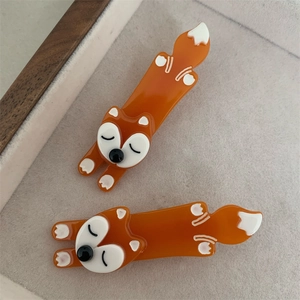 Macro shot of two orange acetate fox hair clips inside a beige velvet jewelry box