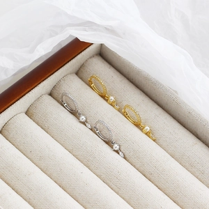 Detailed view of gold and silver pearl drop earrings in a luxury jewelry display box