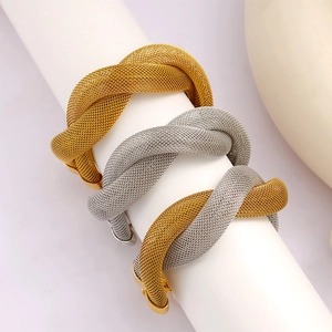 Detail of twisted mesh bracelets in gold, silver, and two-tone finishes on a white display
