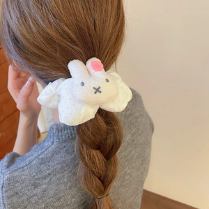 Detailed view of a plush white bunny with polka dot scrunchie worn on a high ponytail