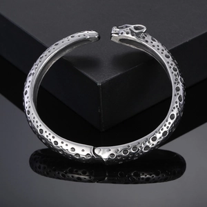 Detail of silver panther head open bangle with polished leopard spot texture on steel