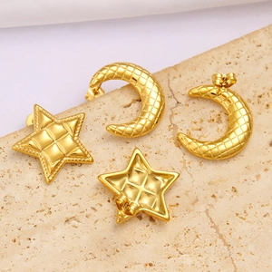 Macro detail of gold star and moon earrings with quilted texture on stone background