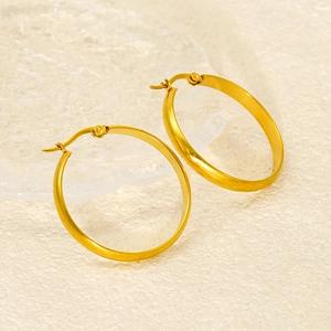 Close-up of gold 18k stainless steel hoop earrings with flat round design on beige background