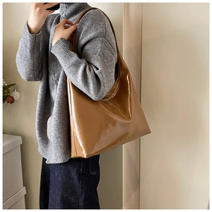 Dettaglio di una grande borsa tote lucida color caramello indossata da modella