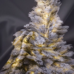 Detail of soft fabric texture featuring a snowy Christmas tree print and warm lights