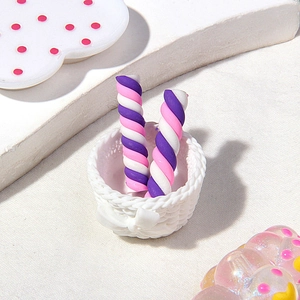 Close-up of colorful spiral candy clay charms in a miniature white woven basket