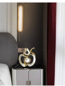 Detail of a minimalist white ceramic apple sculpture with elegant gold accents