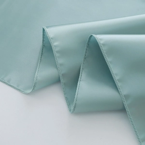 Detailed view of light blue satin table runner fabric texture and hemmed edge stitching