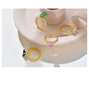 Macro shot of four emerald cut gemstone rings in gold plating with pavé set diamond bands