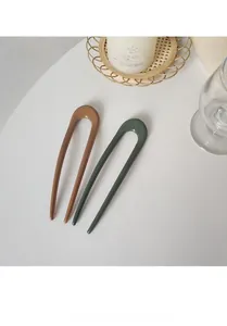 Minimalist U-shaped hair pins in brown and dark green colors for elegant bun hairstyles