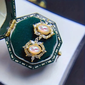 Macro shot of gold oval opal earrings with marquise zircons in a velvet gift box