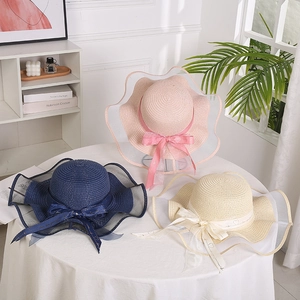 Straw sun hats in pink, navy, and beige with wavy mesh brims and ribbon bows