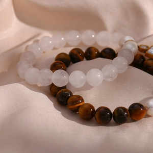 Detail of beaded bracelet with tiger eye stones, white pearls and golden cross charm