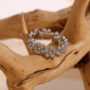Détail d'une bague fleur argentée avec zircons posée sur une texture de bois naturel