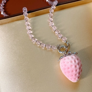 Close-up of pink velvet strawberry pendant necklace with faceted crystal beads detailing