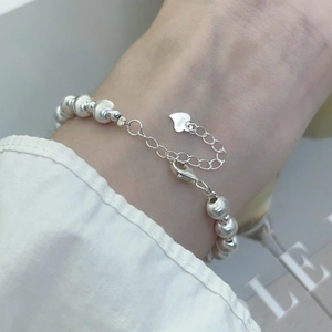 Detailed macro view of S925 sterling silver beaded bracelet with heart charm and stamp