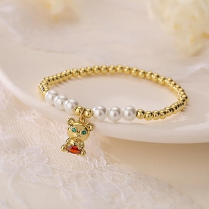 Gold-plated bear charm bracelet with pearls and colorful cubic zirconia on lace background