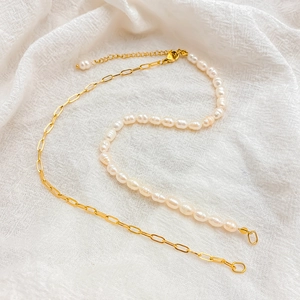 Detail of asymmetrical necklace with freshwater pearls and golden paperclip chain link
