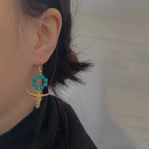 Vintage western turquoise bead earrings with gold bull skull pendant worn by a model