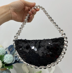 Detail of black sequined crescent bag with large crystal handle for evening parties