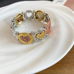 Close-up of tricolor heart-themed elastic beaded bracelet with rhinestones on a white tray